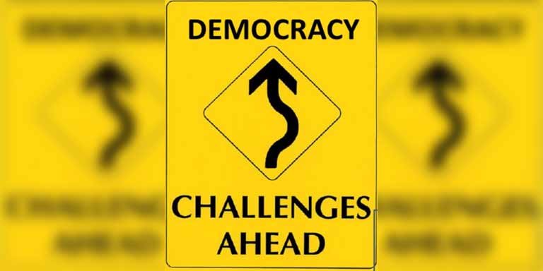 yellow traffic sign that says democracy challenges ahead