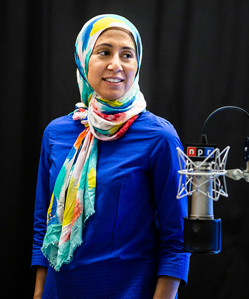 Alumna Asma Khalid poses in a blue blouse in one of NPR's podcasting studios.