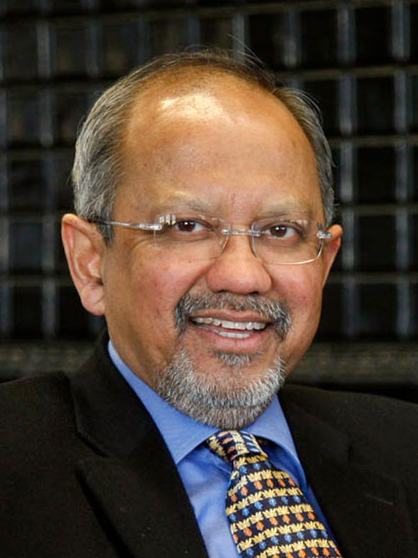A headshot of Sumit Ganguly, who wears a dark suit and a gold-and-black patterned tie.