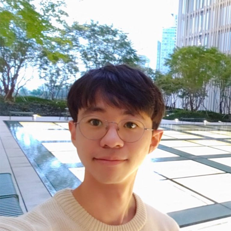 A headshot of Inwoo Lee, who poses outside with a city park and fountain in the background.