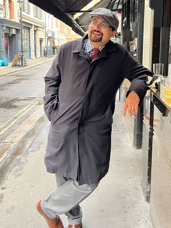 A headshot of Vasabjit Banerjee, who poses outside in a coat and hat.